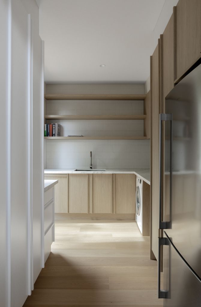 Butler's pantry with timber shelving, marble benchtop, integrated washing machine and tiled splashback