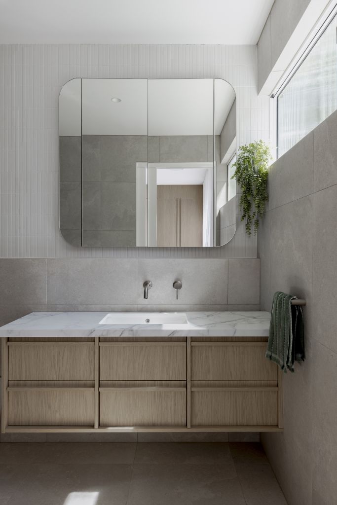 Bathroom vanity with mirrored cabinet, stone tiles, marble benchtop and hanging greenery