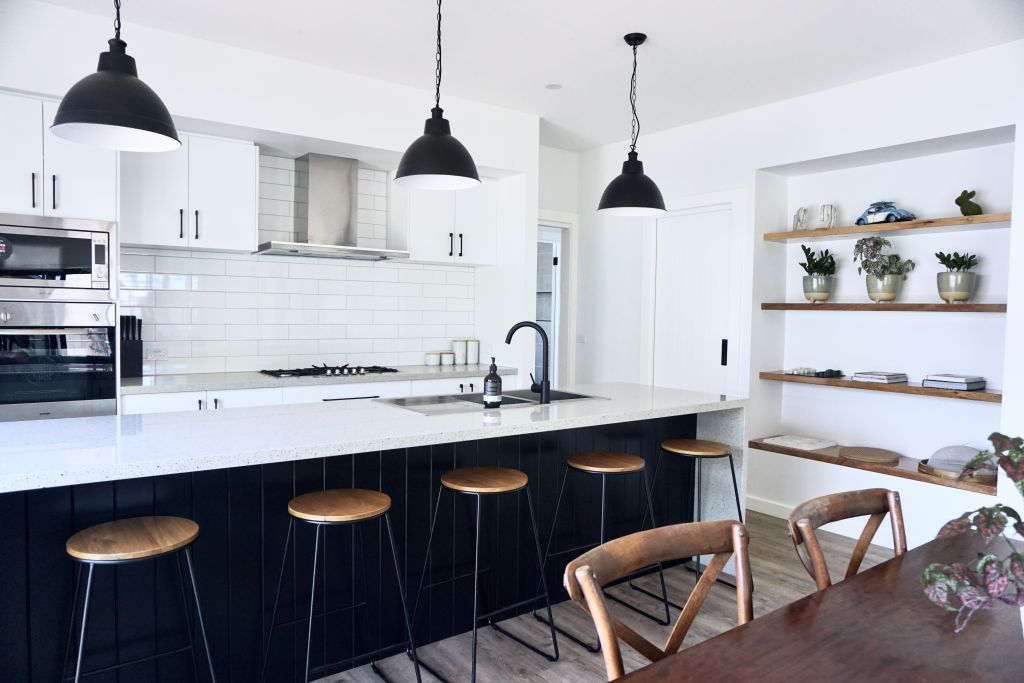 Kitchen with black shaker-style island, white cabinetry, subway tile splashback and timber open shelving
